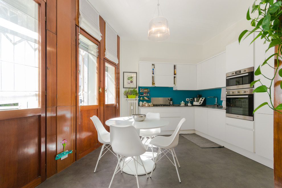 Immagine di una grande cucina a L minimal chiusa con ante lisce, ante bianche, top in laminato, paraspruzzi blu, elettrodomestici in acciaio inossidabile e pavimento grigio