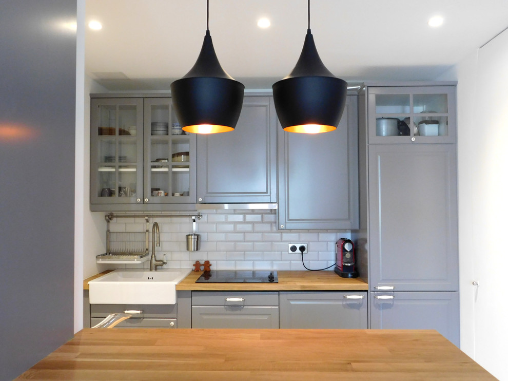 Photo of a medium sized industrial kitchen/diner in Other with a single-bowl sink, raised-panel cabinets, grey cabinets, wood worktops, white splashback, ceramic splashback, stainless steel appliances, dark hardwood flooring and an island.