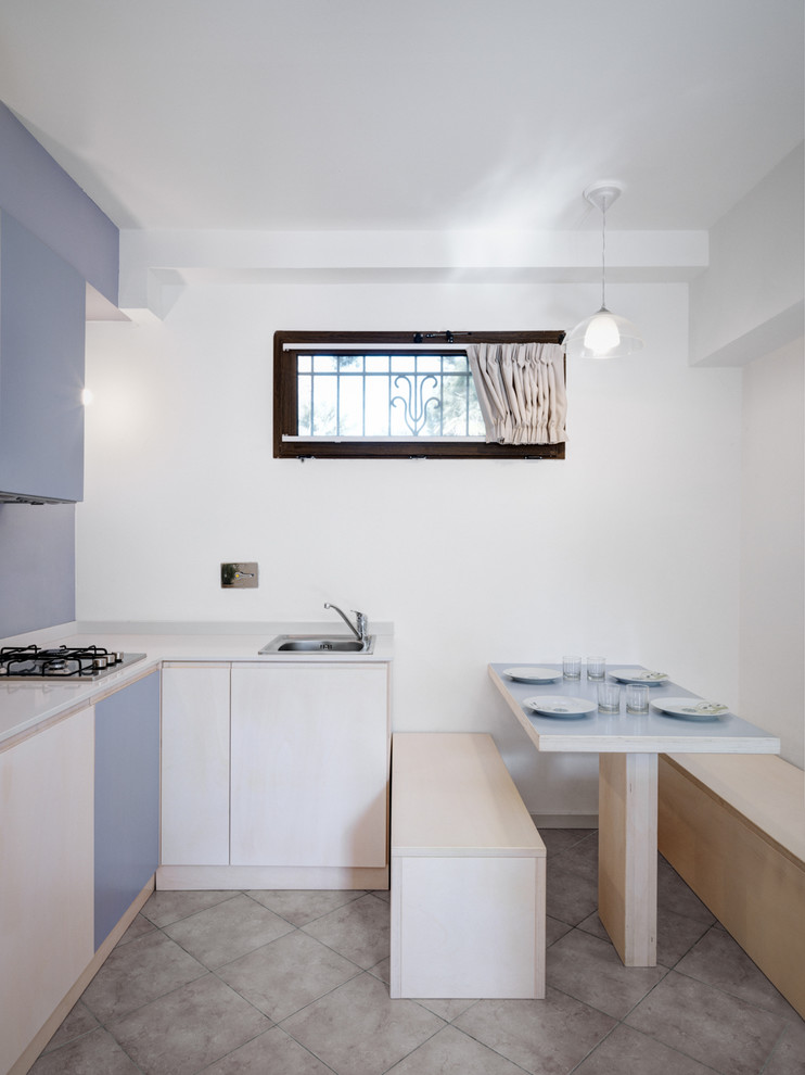 Kleine Moderne Wohnküche in L-Form mit flächenbündigen Schrankfronten, blauen Schränken, Küchenrückwand in Blau, Halbinsel, grauem Boden und weißer Arbeitsplatte in Sonstige