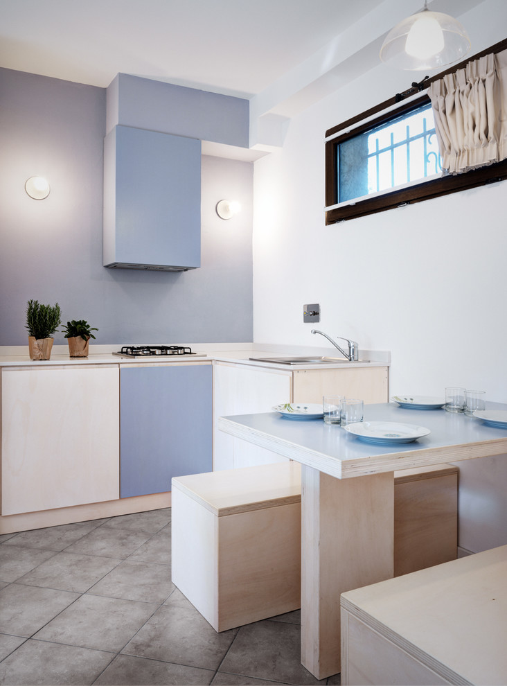 Small coastal l-shaped kitchen/diner in Other with flat-panel cabinets, grey floors, white worktops, blue cabinets, blue splashback, a built-in sink and no island.