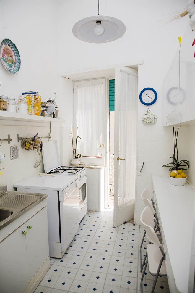 Exempel på ett medelhavsstil kök, med vita skåp, vita vitvaror, släta luckor och flerfärgat golv