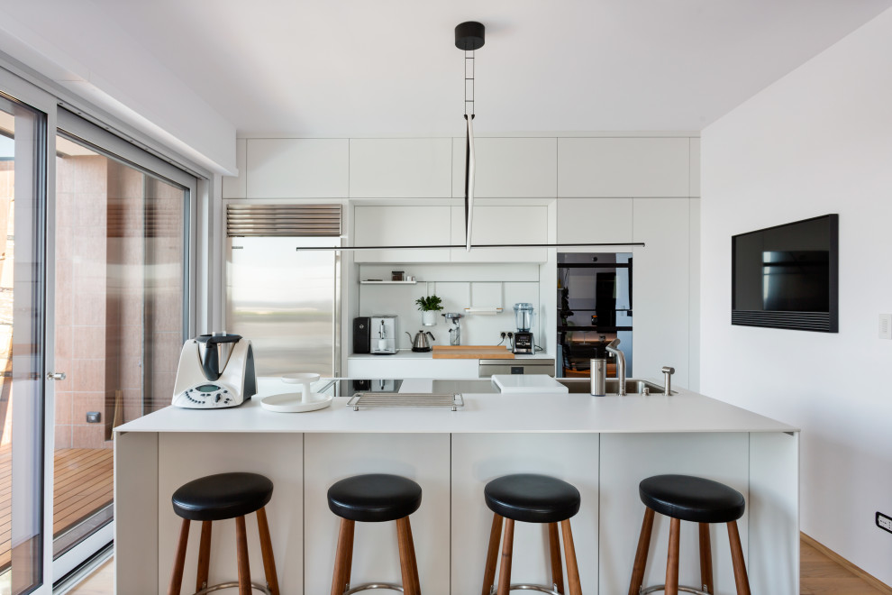 Design ideas for a large kitchen in Milan with flat-panel cabinets, white splashback, stainless steel appliances, an island, white worktops, a submerged sink, white cabinets and medium hardwood flooring.