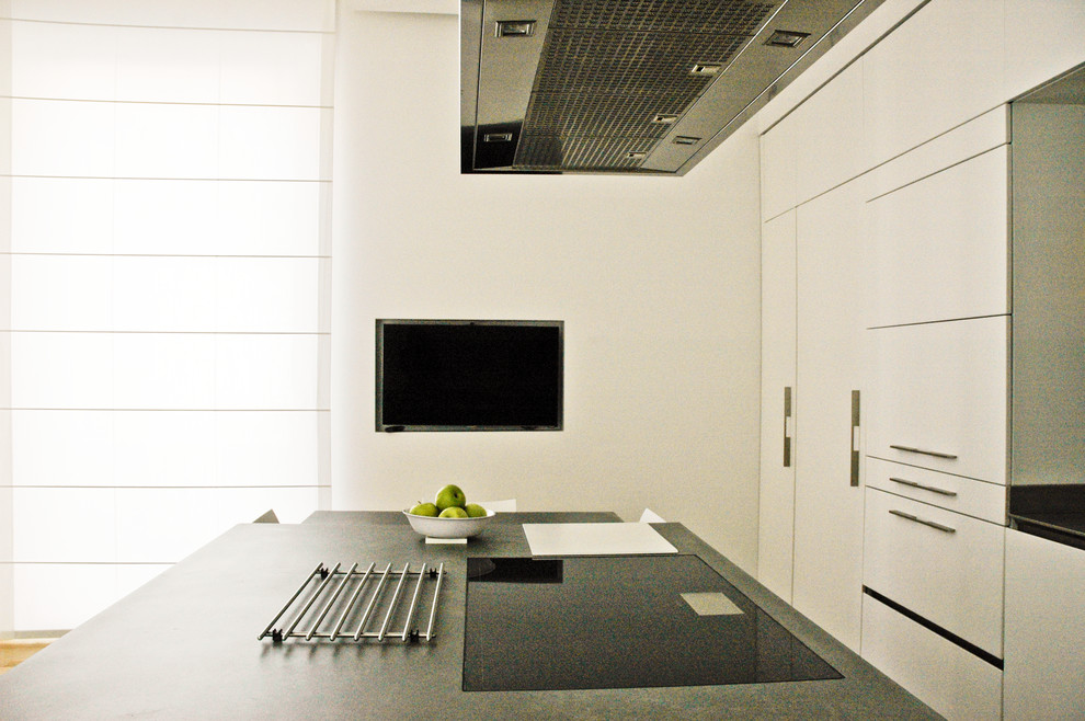 Foto di una cucina minimal con lavello integrato, ante bianche, top in superficie solida e elettrodomestici in acciaio inossidabile