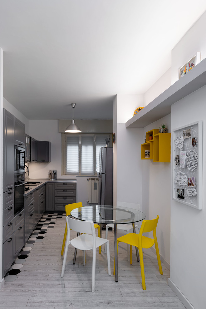 Foto på ett litet funkis grå kök, med en integrerad diskho, luckor med upphöjd panel, grå skåp, laminatbänkskiva, grått stänkskydd, stänkskydd i keramik, svarta vitvaror, klinkergolv i porslin och grått golv