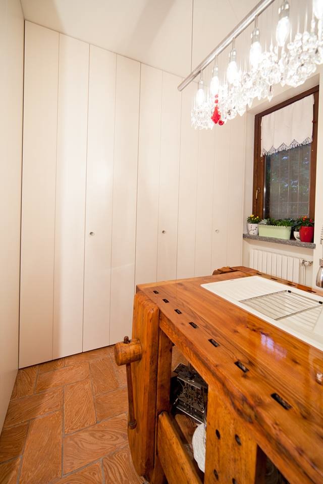 Diseño de cocina de estilo de casa de campo pequeña con fregadero encastrado, armarios con paneles lisos, puertas de armario de madera clara, encimera de madera, electrodomésticos blancos, suelo de baldosas de terracota y una isla