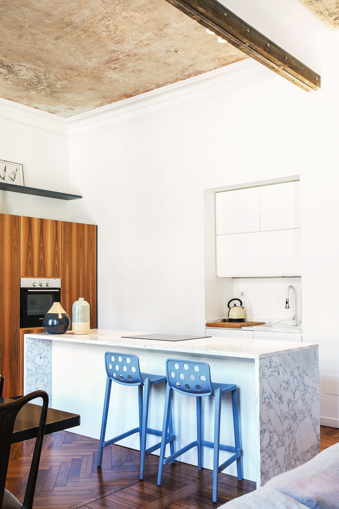 Offene, Mittelgroße Moderne Küche in L-Form mit flächenbündigen Schrankfronten, weißen Schränken, Küchengeräten aus Edelstahl, braunem Holzboden, Kücheninsel, braunem Boden, Marmor-Arbeitsplatte und Küchenrückwand in Weiß in Turin