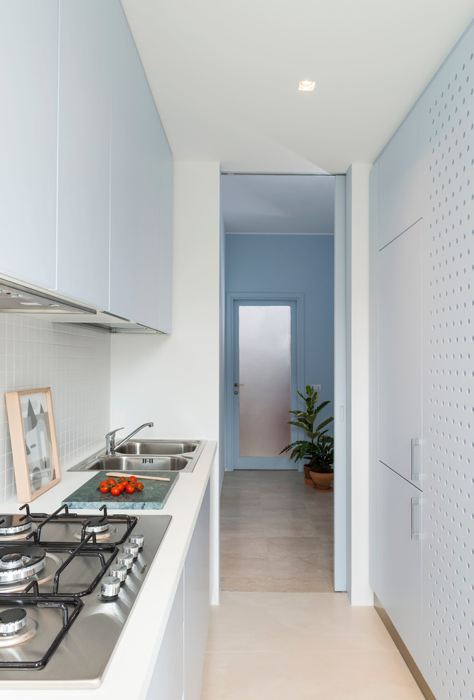 Small contemporary galley enclosed kitchen in Milan with a double-bowl sink, flat-panel cabinets, white cabinets, composite countertops, white splashback and ceramic splashback.
