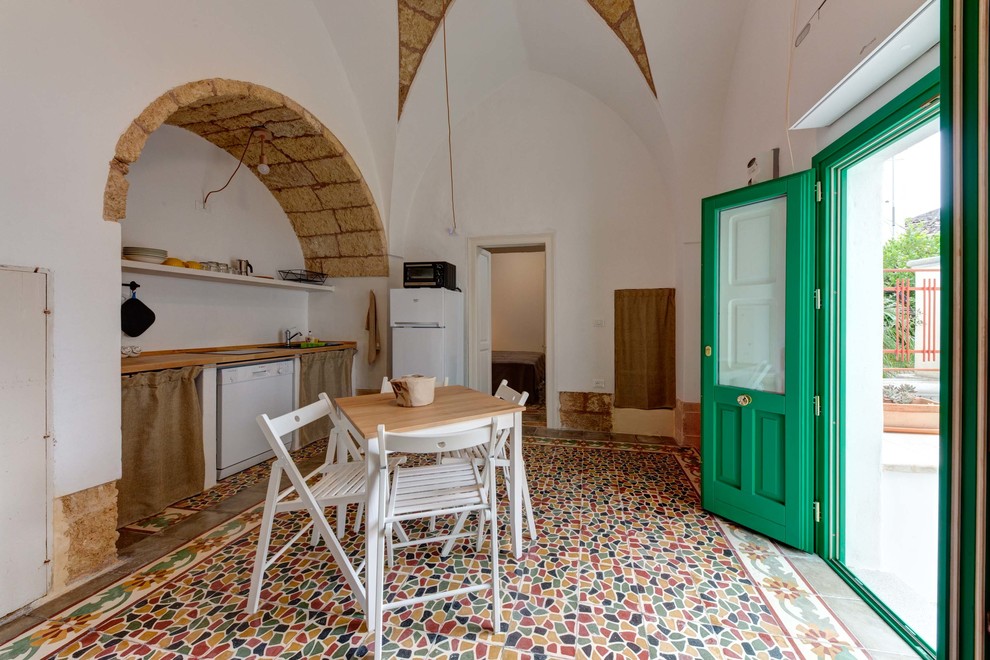 На фото: прямая кухня в средиземноморском стиле с открытыми фасадами, деревянной столешницей, белой техникой и обеденным столом без острова с