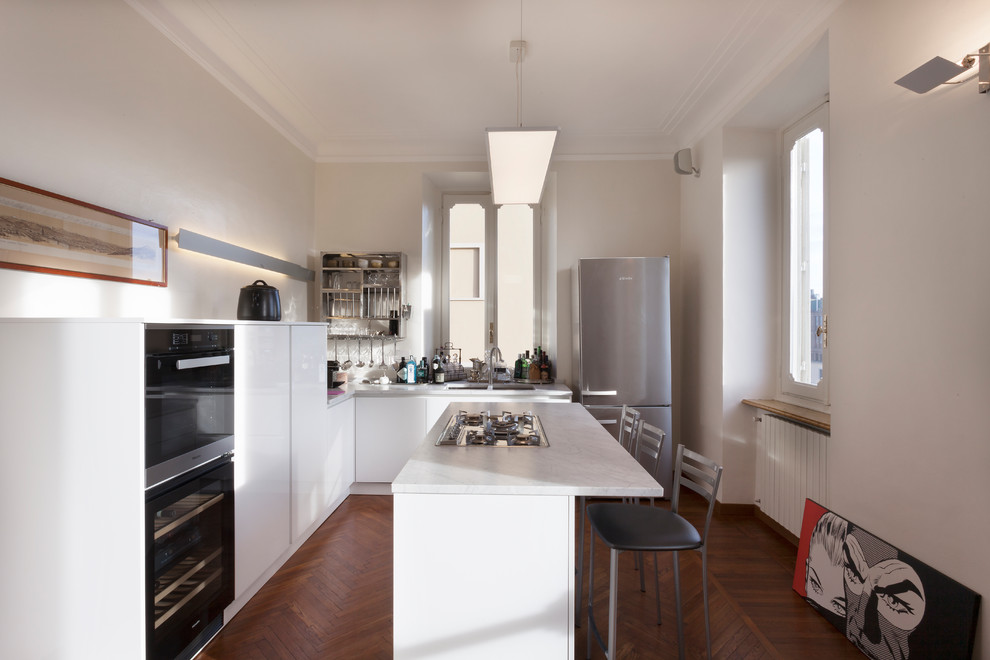 Immagine di una cucina minimal di medie dimensioni con ante lisce, ante bianche, top in marmo, lavello a doppia vasca, elettrodomestici neri e pavimento in legno massello medio
