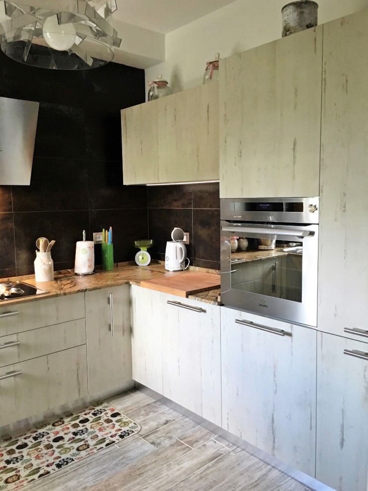 Bild på ett avskilt, mellanstort industriellt u-kök, med en nedsänkt diskho, släta luckor, skåp i ljust trä, marmorbänkskiva, stänkskydd i porslinskakel, rostfria vitvaror och klinkergolv i porslin