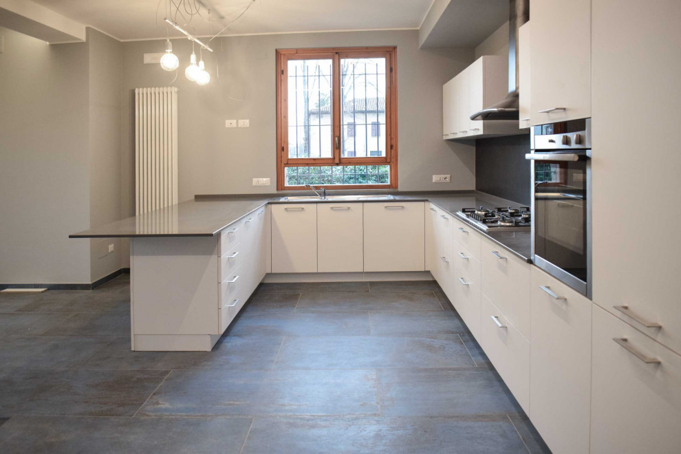 Modern inredning av ett stort grå grått kök, med en dubbel diskho, släta luckor, vita skåp, bänkskiva i kvarts, svart stänkskydd, stänkskydd i porslinskakel, rostfria vitvaror, klinkergolv i porslin, en halv köksö och grått golv