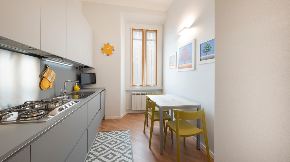Einzeilige Moderne Küche ohne Insel mit flächenbündigen Schrankfronten, grauen Schränken, braunem Holzboden, braunem Boden und grauer Arbeitsplatte in Mailand