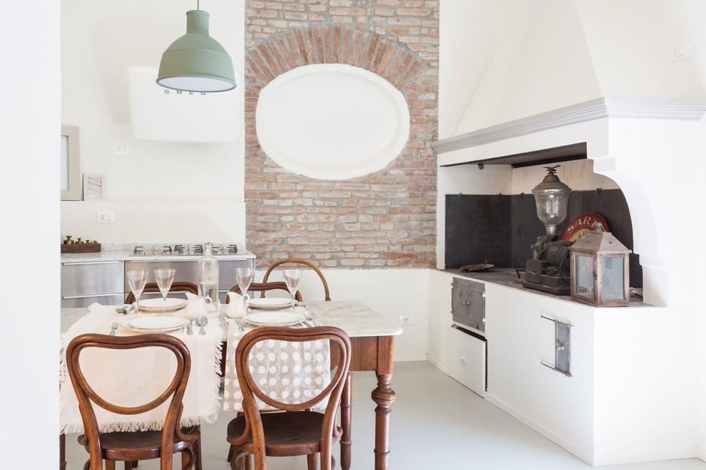 Стильный дизайн: угловая кухня в средиземноморском стиле с обеденным столом, плоскими фасадами, фасадами из нержавеющей стали и серым полом - последний тренд