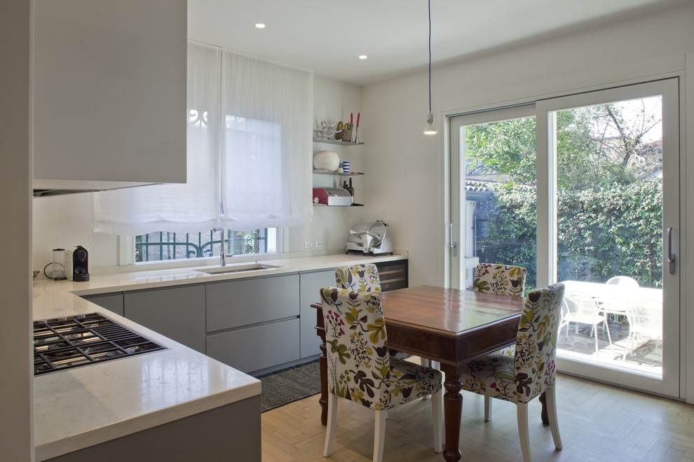 Inspiration for a medium sized contemporary l-shaped enclosed kitchen in Other with a built-in sink, flat-panel cabinets, grey cabinets, marble worktops, beige splashback, marble splashback, black appliances, light hardwood flooring, no island and beige worktops.