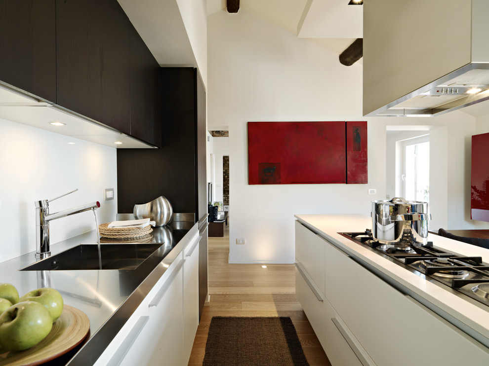 Modelo de cocina actual con fregadero de un seno, armarios con paneles lisos, suelo de madera clara, encimera de acero inoxidable y con blanco y negro
