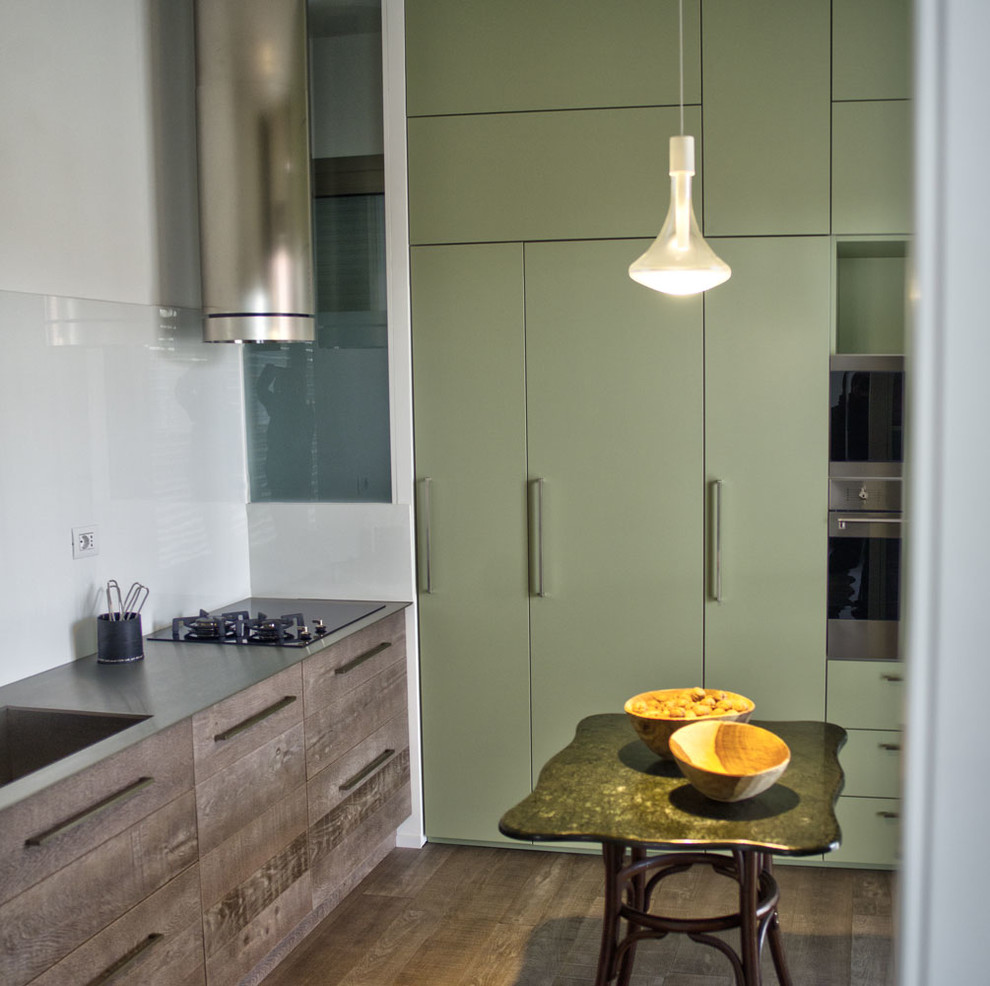 Idéer för ett avskilt, mellanstort modernt linjärt kök, med en integrerad diskho, gröna skåp, bänkskiva i rostfritt stål, vitt stänkskydd, mellanmörkt trägolv och brunt golv