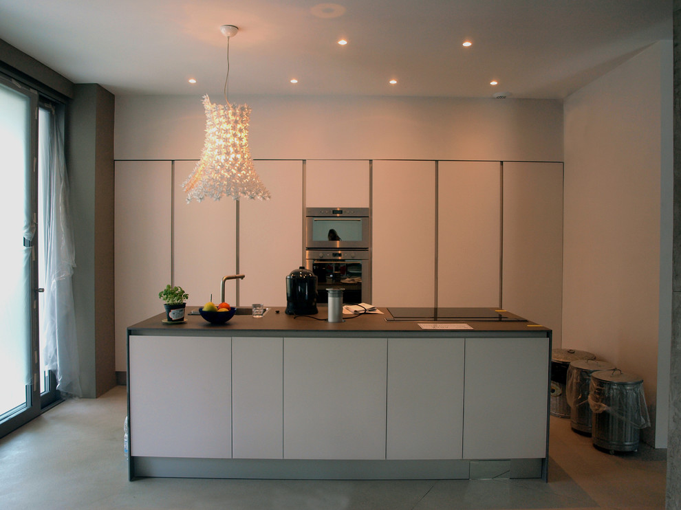 This is an example of a small contemporary single-wall kitchen/diner in Milan with flat-panel cabinets, white cabinets and an island.
