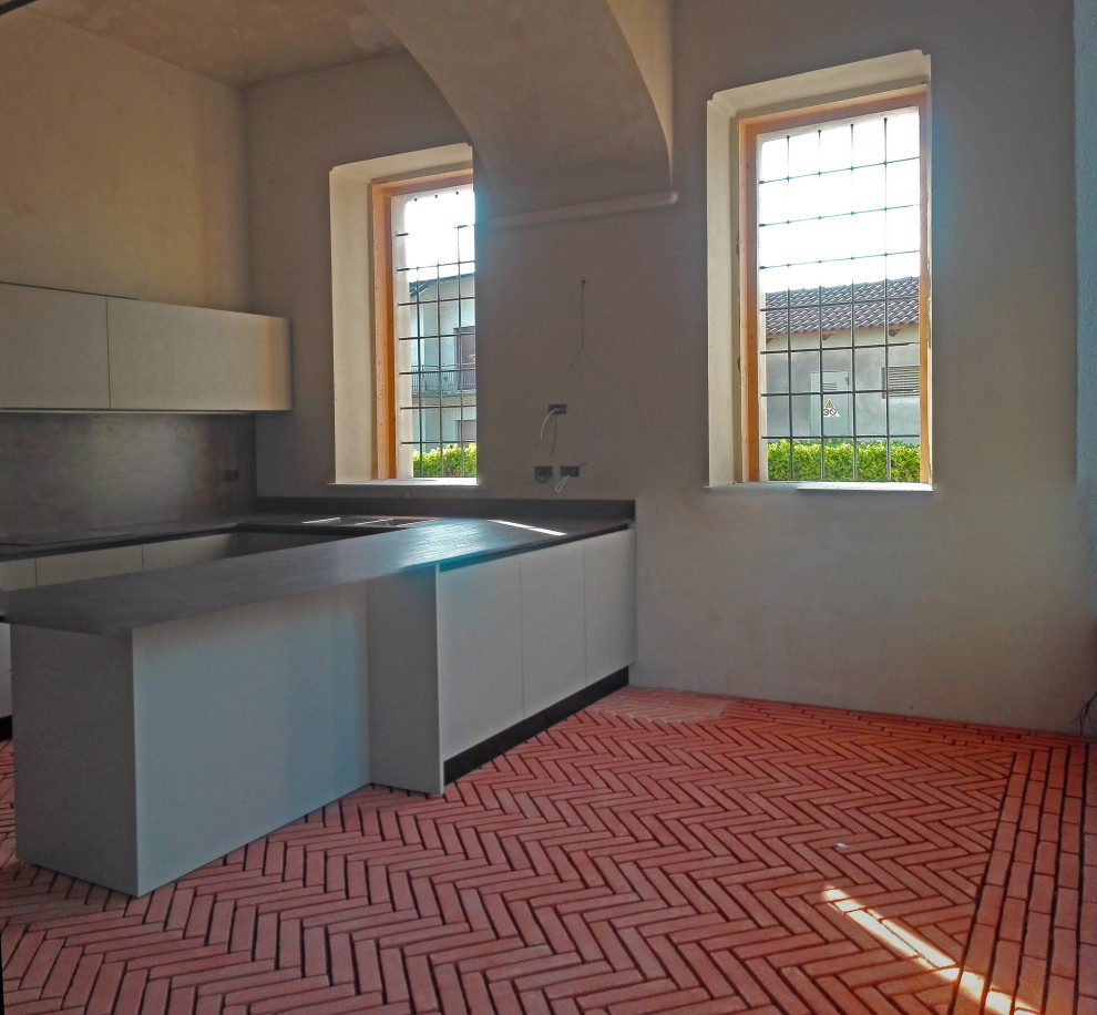 На фото: большая кухня-гостиная в стиле рустика с красным полом и сводчатым потолком