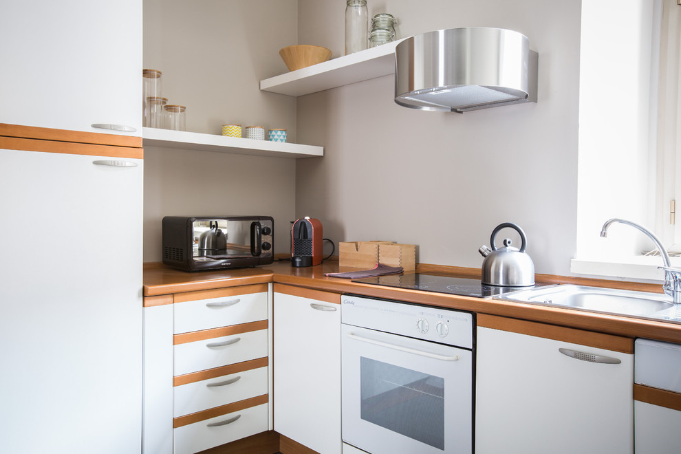 На фото: маленькая угловая кухня-гостиная в скандинавском стиле с накладной мойкой, белыми фасадами и деревянной столешницей без острова для на участке и в саду