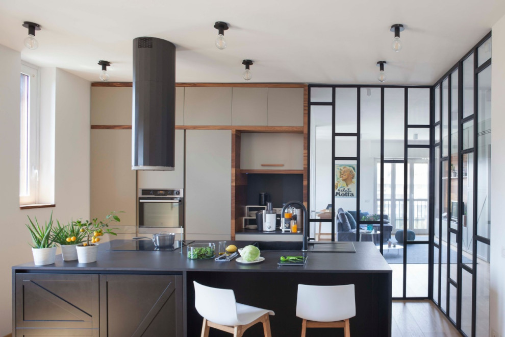 Foto di una cucina contemporanea chiusa e di medie dimensioni con lavello da incasso, ante lisce, ante grigie, elettrodomestici da incasso, pavimento marrone e top nero