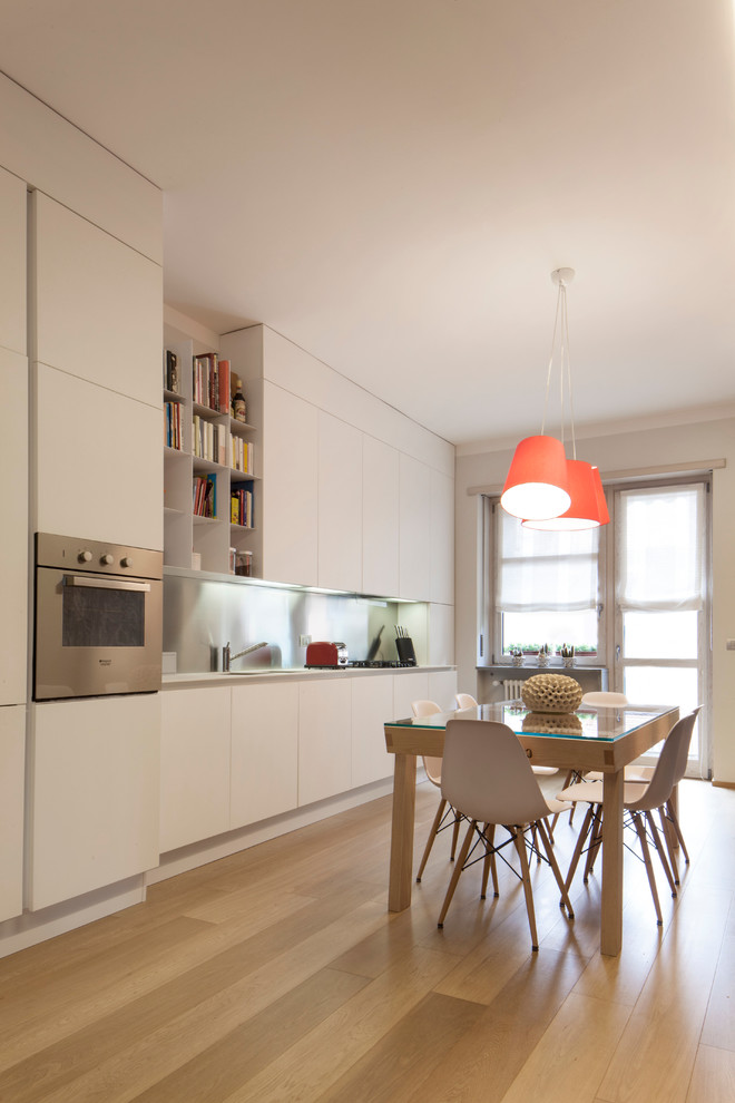 Example of a mid-sized trendy single-wall light wood floor open concept kitchen design in Turin with an undermount sink, flat-panel cabinets, white cabinets, quartz countertops and stainless steel appliances