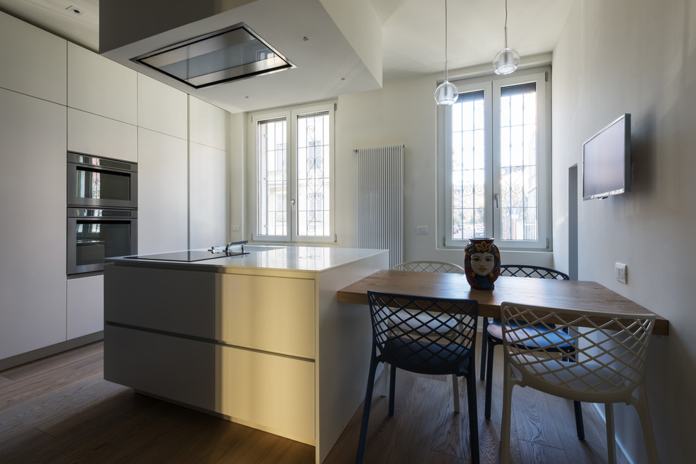 Foto di una cucina minimal chiusa e di medie dimensioni con lavello integrato, ante lisce, ante bianche, parquet chiaro e pavimento beige