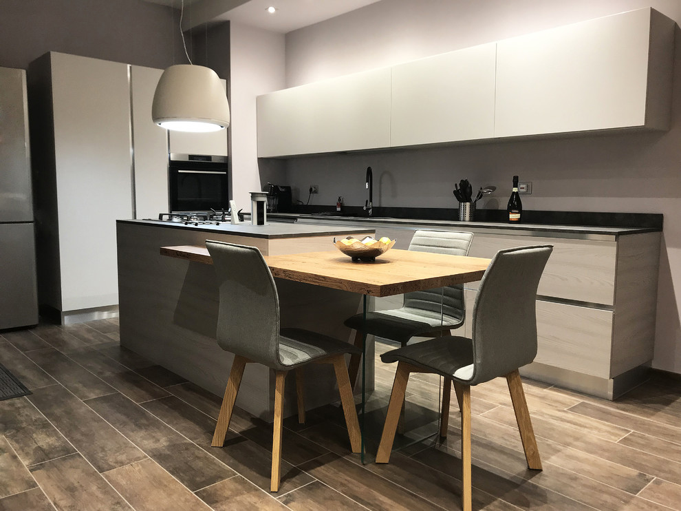 Inspiration for a large modern l-shaped kitchen/diner in Other with a double-bowl sink, flat-panel cabinets, grey cabinets, wood worktops, stainless steel appliances, porcelain flooring, an island, multi-coloured floors and black worktops.