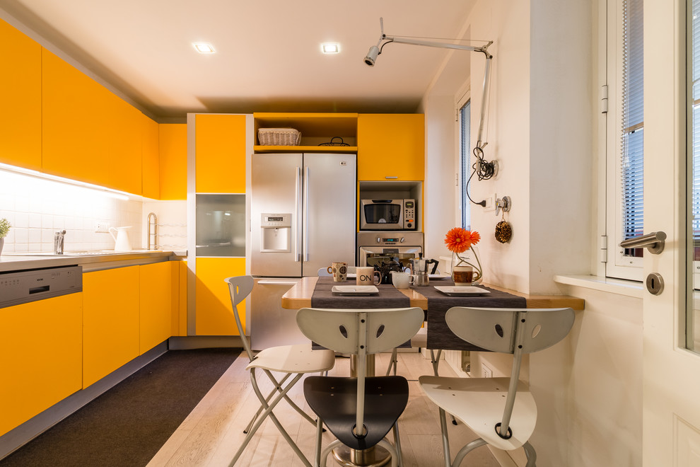 Idee per una cucina design con ante lisce, paraspruzzi bianco, ante gialle, elettrodomestici in acciaio inossidabile e top grigio