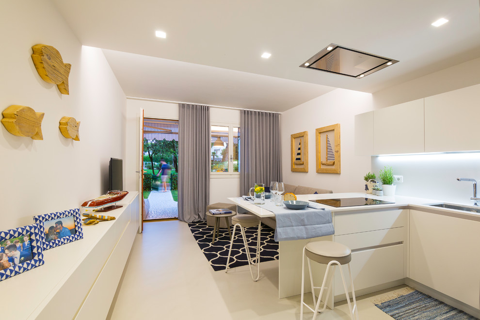 Example of a small beach style beige floor open concept kitchen design in Venice with flat-panel cabinets, solid surface countertops, white backsplash, white countertops, an undermount sink, white cabinets and a peninsula
