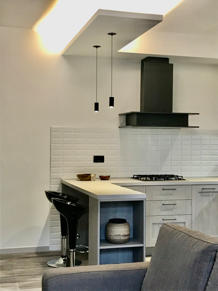 Foto på ett mellanstort industriellt grå kök, med en integrerad diskho, luckor med upphöjd panel, skåp i slitet trä, vitt stänkskydd, stänkskydd i tunnelbanekakel, rostfria vitvaror, laminatgolv och en halv köksö