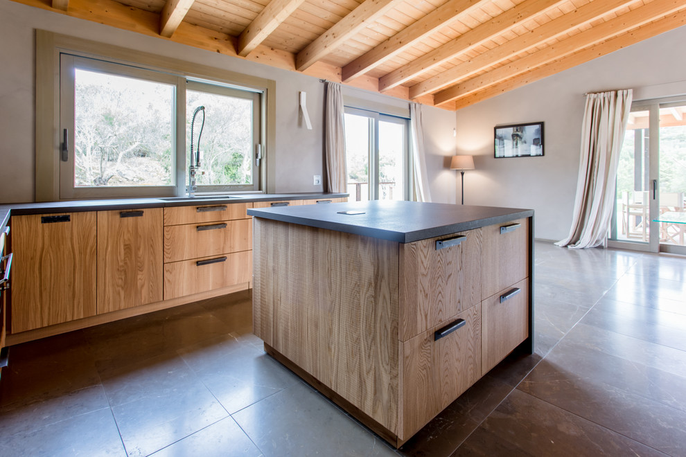 Idées déco pour une cuisine américaine encastrable méditerranéenne en L et bois brun avec îlot, plan de travail noir, un évier 1 bac, un placard à porte plane et un sol marron.