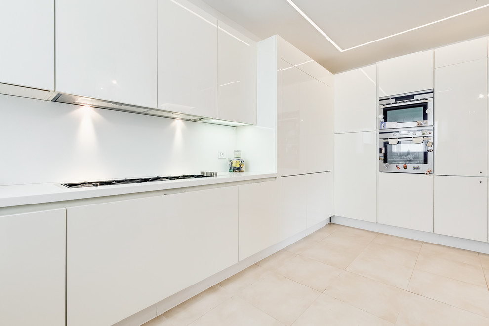 Foto di un'ampia cucina design con ante lisce, ante bianche, paraspruzzi bianco, elettrodomestici in acciaio inossidabile, pavimento in gres porcellanato, pavimento beige e top bianco