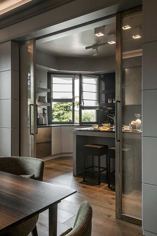 Immagine di un cucina con isola centrale minimal chiuso e di medie dimensioni con ante lisce, paraspruzzi nero e paraspruzzi con lastra di vetro