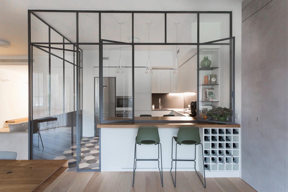 This is an example of a large contemporary l-shaped enclosed kitchen in Other with flat-panel cabinets, white cabinets, composite countertops, black splashback, porcelain flooring, a breakfast bar, grey floors and black worktops.