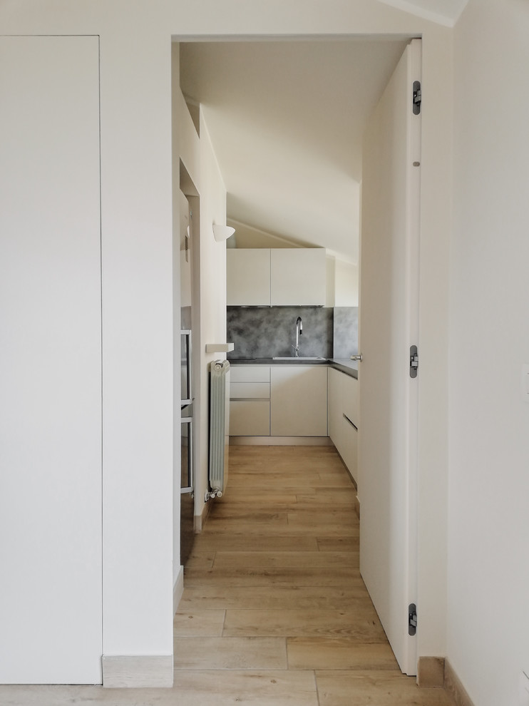 Foto de cocina minimalista de tamaño medio cerrada con armarios con paneles lisos, puertas de armario blancas, encimera de laminado, salpicadero verde, electrodomésticos de acero inoxidable y encimeras grises