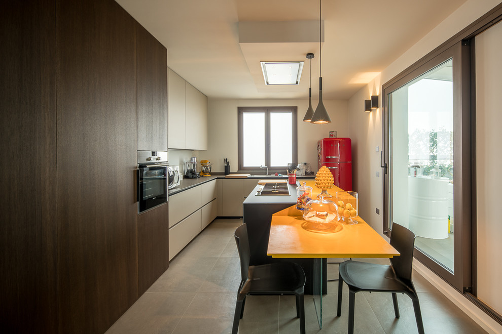 Große Moderne Küche in L-Form mit flächenbündigen Schrankfronten, Küchenrückwand in Weiß, grauem Boden, Unterbauwaschbecken, beigen Schränken und bunten Elektrogeräten in Bologna