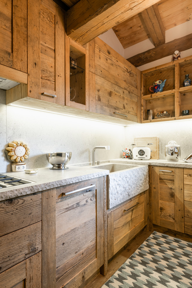 Foto på ett litet rustikt grå kök, med en rustik diskho, luckor med infälld panel, skåp i mellenmörkt trä, bänkskiva i kalksten, grått stänkskydd, stänkskydd i kalk, rostfria vitvaror och mellanmörkt trägolv