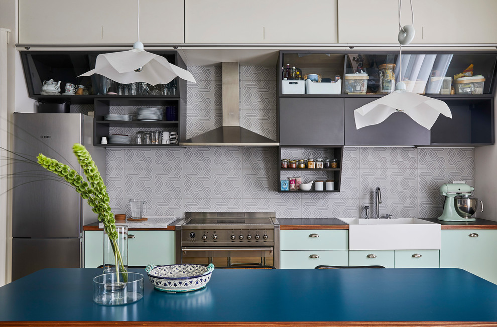 Inspiration för mellanstora moderna linjära grått kök med öppen planlösning, med en enkel diskho, släta luckor, grå skåp, laminatbänkskiva, grått stänkskydd, stänkskydd i keramik, rostfria vitvaror och ljust trägolv