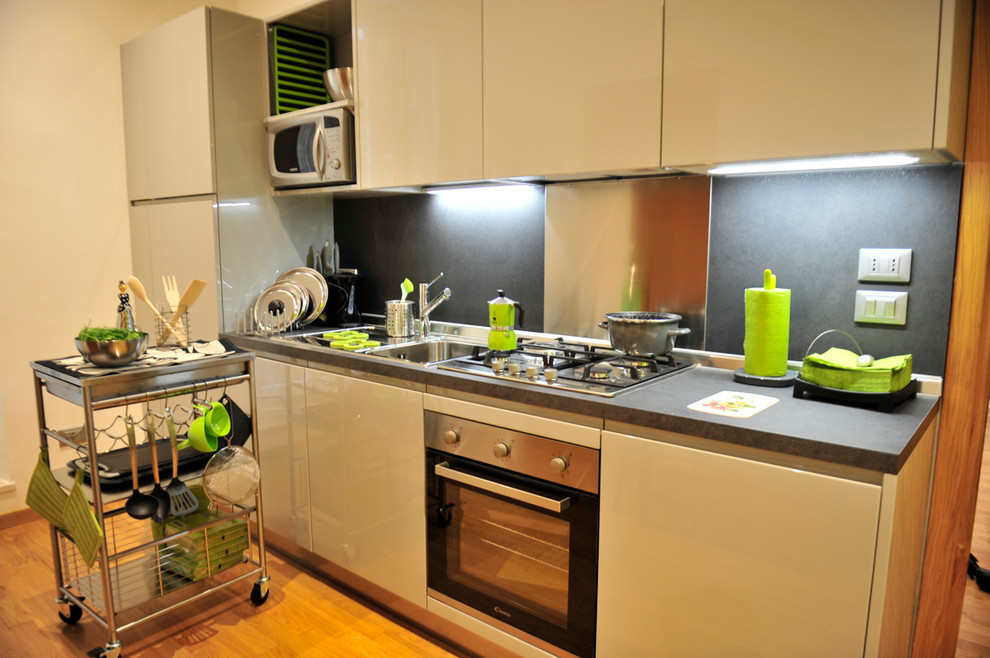 Immagine di una piccola cucina moderna con lavello da incasso, ante lisce, ante grigie, top in laminato, paraspruzzi grigio, elettrodomestici in acciaio inossidabile e parquet chiaro