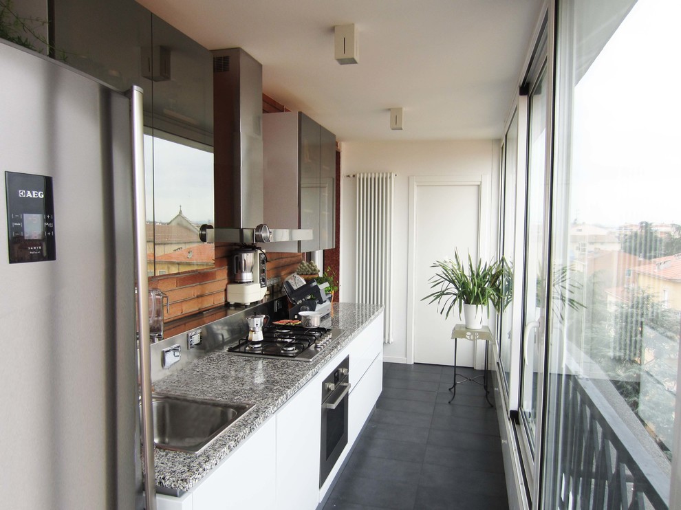 Small modern galley enclosed kitchen in Bologna with a built-in sink, glass-front cabinets, white cabinets, granite worktops, brown splashback, brick splashback, stainless steel appliances, porcelain flooring and black floors.