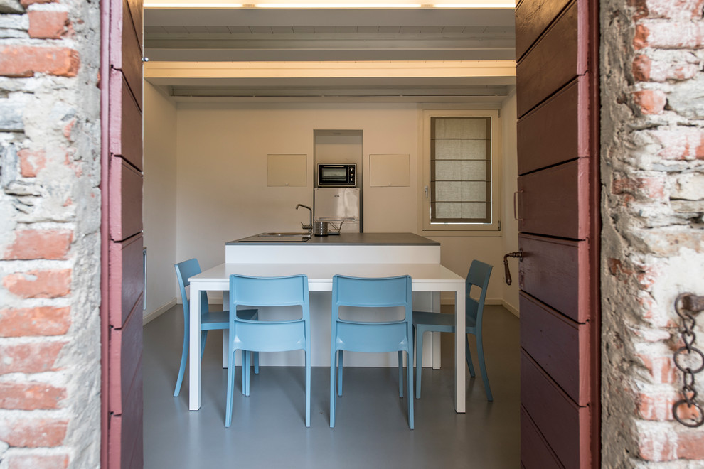 Bild på ett stort funkis kök med öppen planlösning, med en nedsänkt diskho, släta luckor, vita skåp, bänkskiva i kvartsit, rostfria vitvaror, betonggolv, en köksö och grått golv