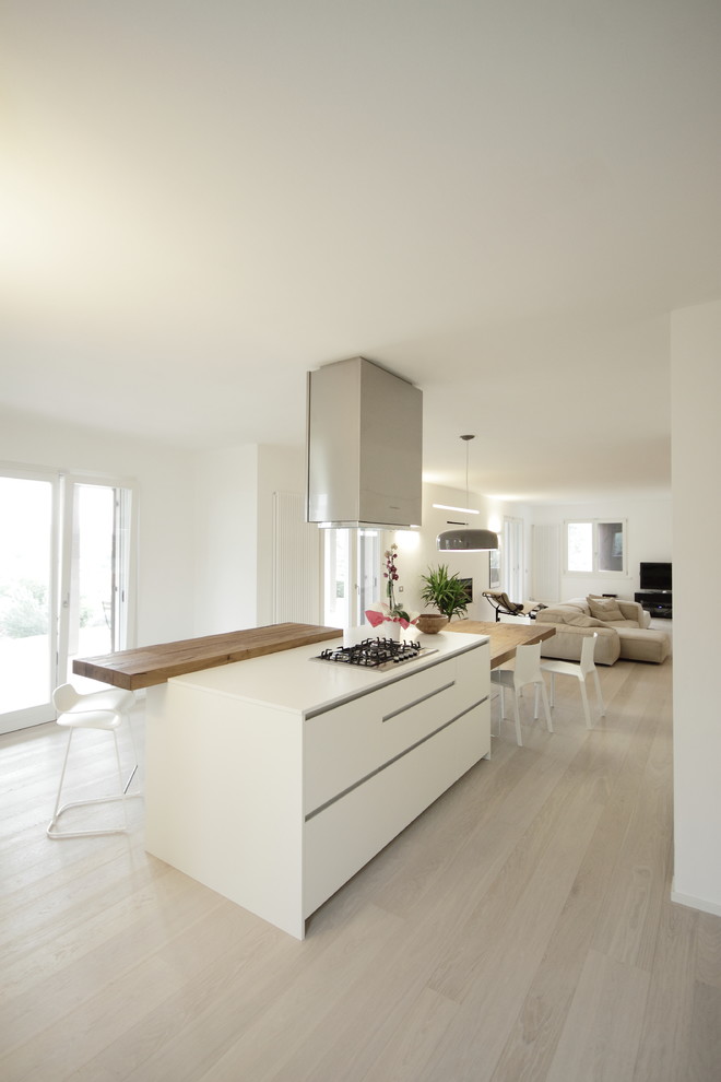 Imagen de cocina actual abierta con armarios con paneles lisos, puertas de armario blancas, suelo de madera clara y una isla