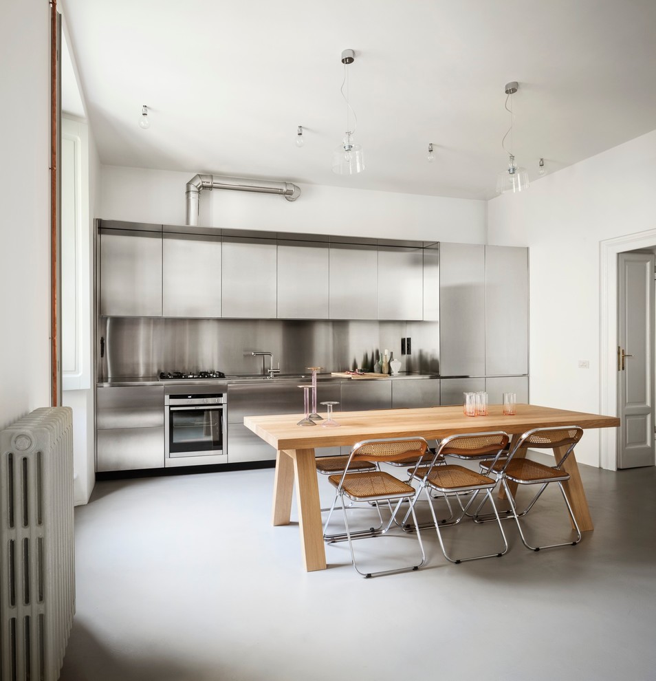 Exempel på ett stort modernt linjärt kök och matrum, med släta luckor, skåp i rostfritt stål, bänkskiva i rostfritt stål, grått stänkskydd och rostfria vitvaror