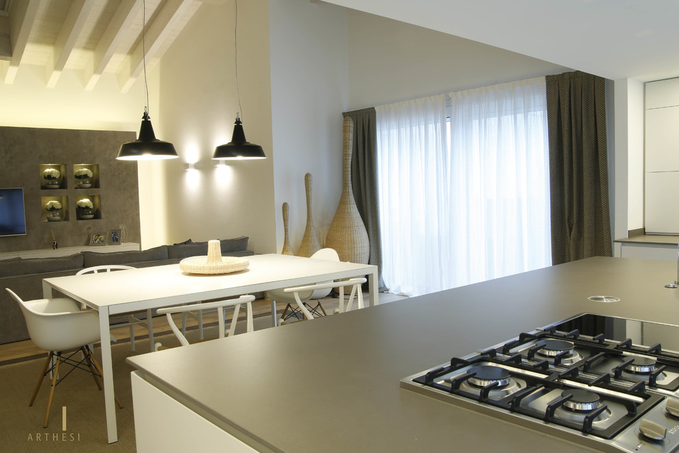 Immagine di un cucina con isola centrale moderno con ante bianche, elettrodomestici in acciaio inossidabile e parquet chiaro