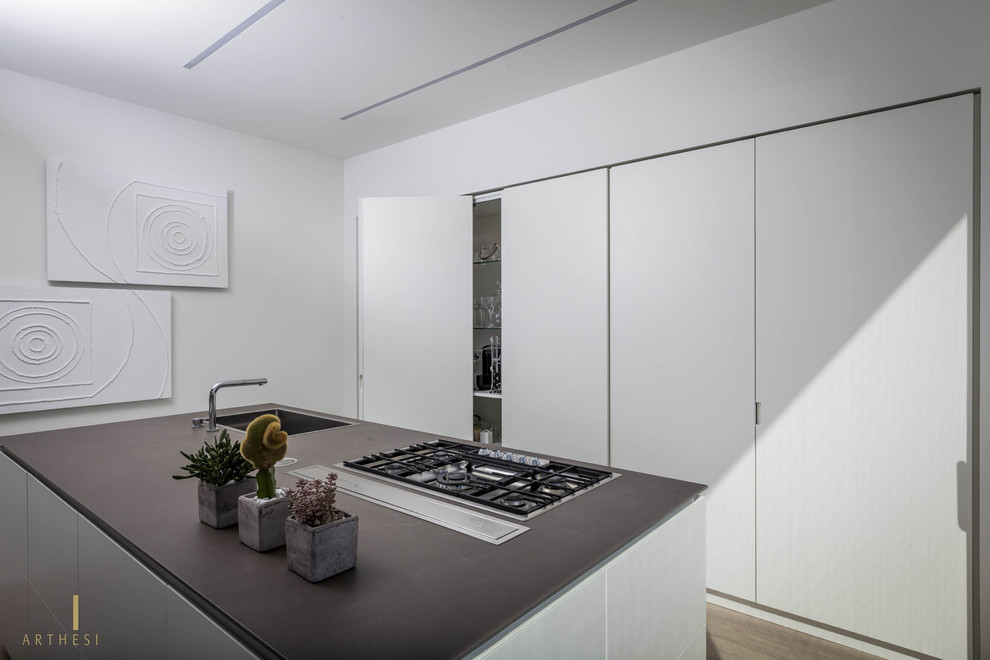 Foto de cocina moderna con fregadero bajoencimera, puertas de armario blancas, encimera de cemento, electrodomésticos de acero inoxidable, suelo de madera clara y una isla