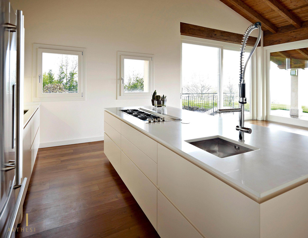 Ispirazione per un cucina con isola centrale moderno con lavello sottopiano, ante bianche, top in quarzo composito e pavimento in legno massello medio