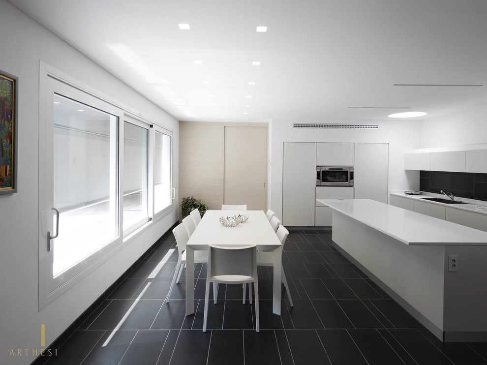 Idee per un cucina con isola centrale moderno con lavello a vasca singola, ante bianche, top in quarzo composito e pavimento in ardesia
