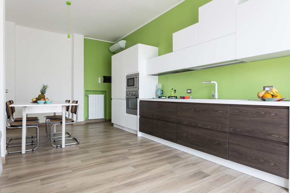 Exempel på ett stort modernt vit linjärt vitt kök och matrum, med grönt stänkskydd, rostfria vitvaror, ljust trägolv, släta luckor och skåp i mörkt trä