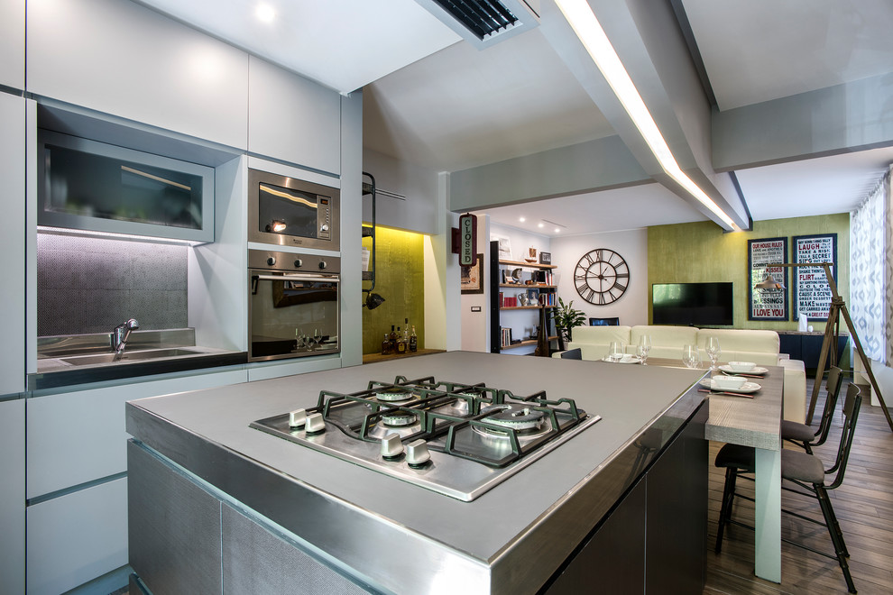 Foto di una cucina industriale di medie dimensioni con lavello integrato, ante lisce, ante grigie, top in acciaio inossidabile e paraspruzzi grigio