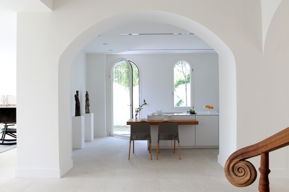 カターニア／パルレモにある地中海スタイルのおしゃれなキッチン (フラットパネル扉のキャビネット、白いキャビネット、トラバーチンの床) の写真